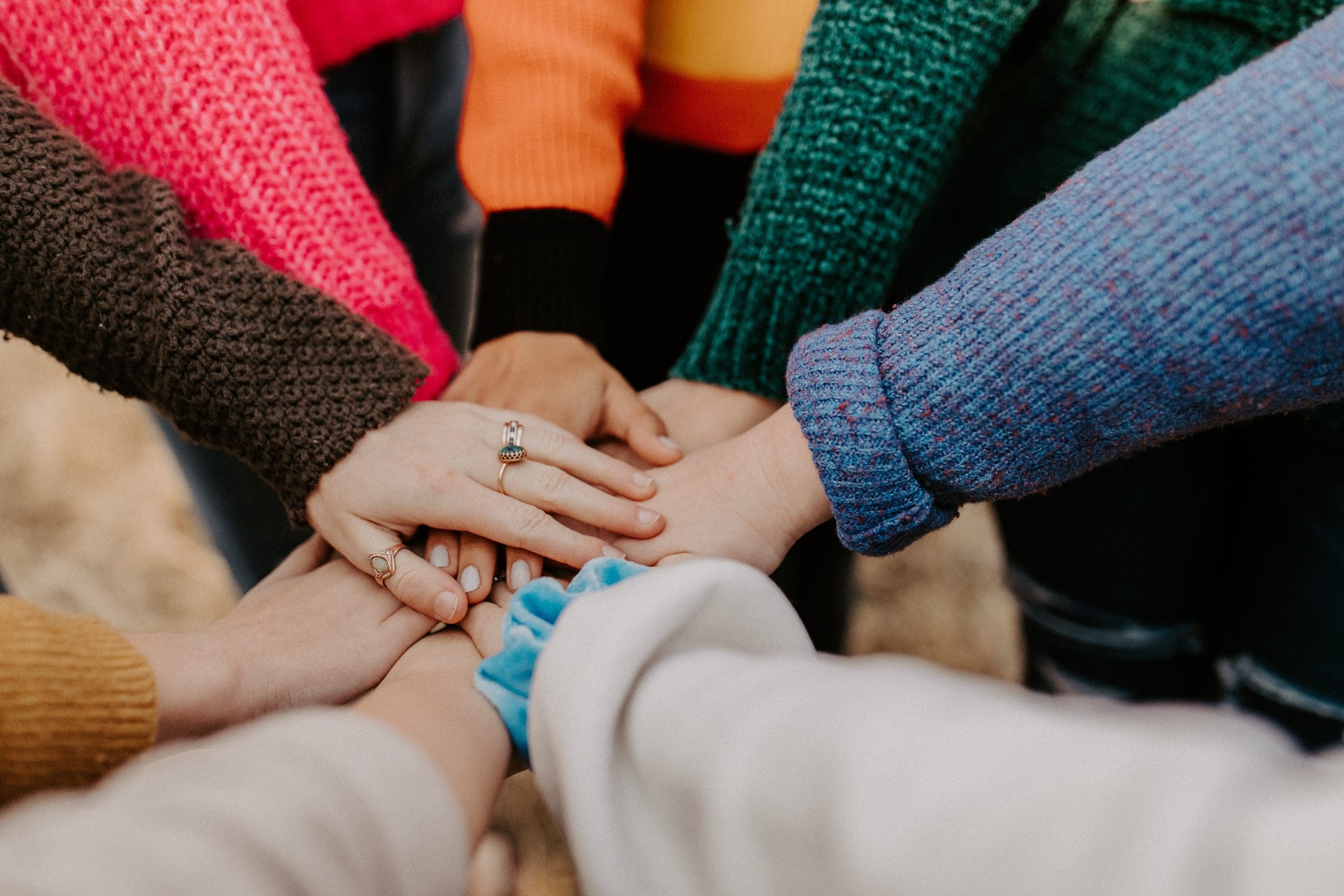 hannah-busing-Zyx1bK9mqmA-unsplash-1 group of hands meeting in the middle