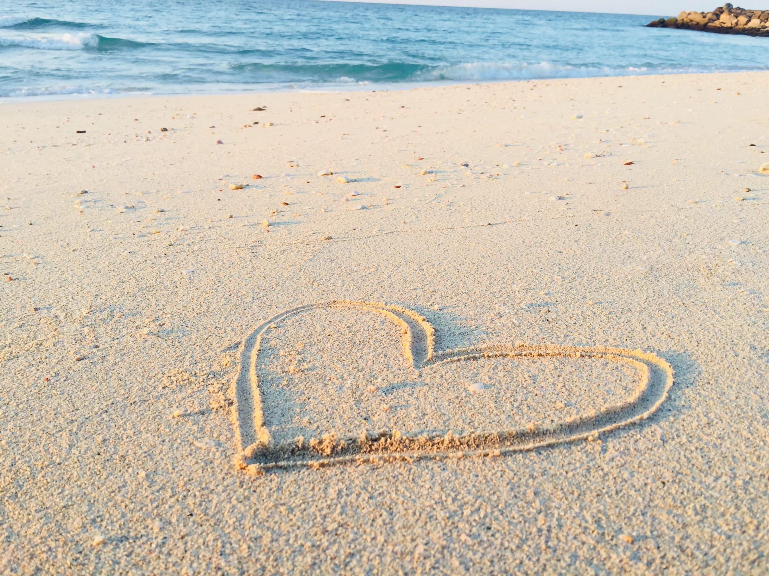 khadeeja-yasser-FHT0KEOwtyg-unsplash heart drawn in sand at the beach